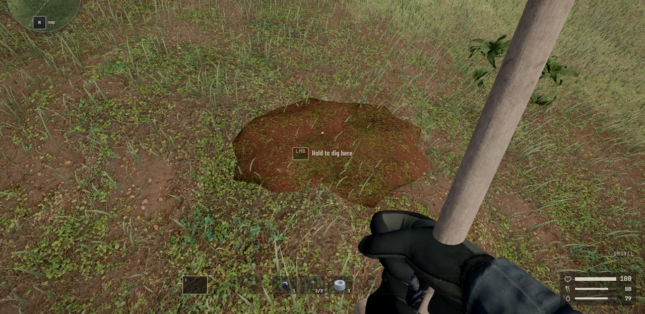 Seen from the eyes, a shovel in the hands, looking down at grass with an oval patch of bare turned earth in it. Over the patch it says: hold to dig here