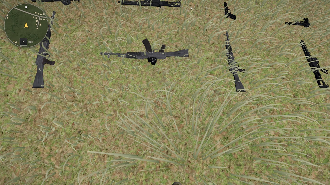 Looking down at grass with several guns lying on it, rifles and submachine guns: each has its magazine in it, and some a sight or a suppressor