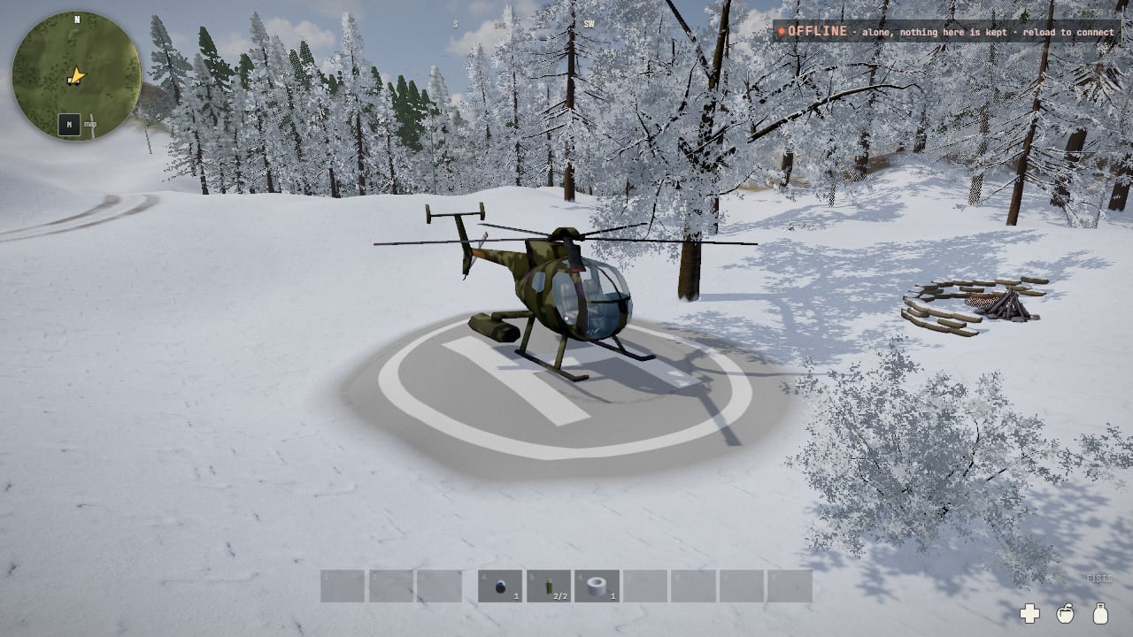 A small camouflaged helicopter standing on a round grey concrete pad painted with a white ring and an H, in snow among frosted pines, a cold fire ring to the right