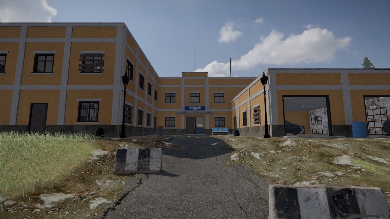 Seen from its drive: a police headquarters in ochre plaster, three blocks round a court, the blue sign Politsiya over the doors at the back of the court, a garage with open doors on the right, lamp posts and striped concrete barriers