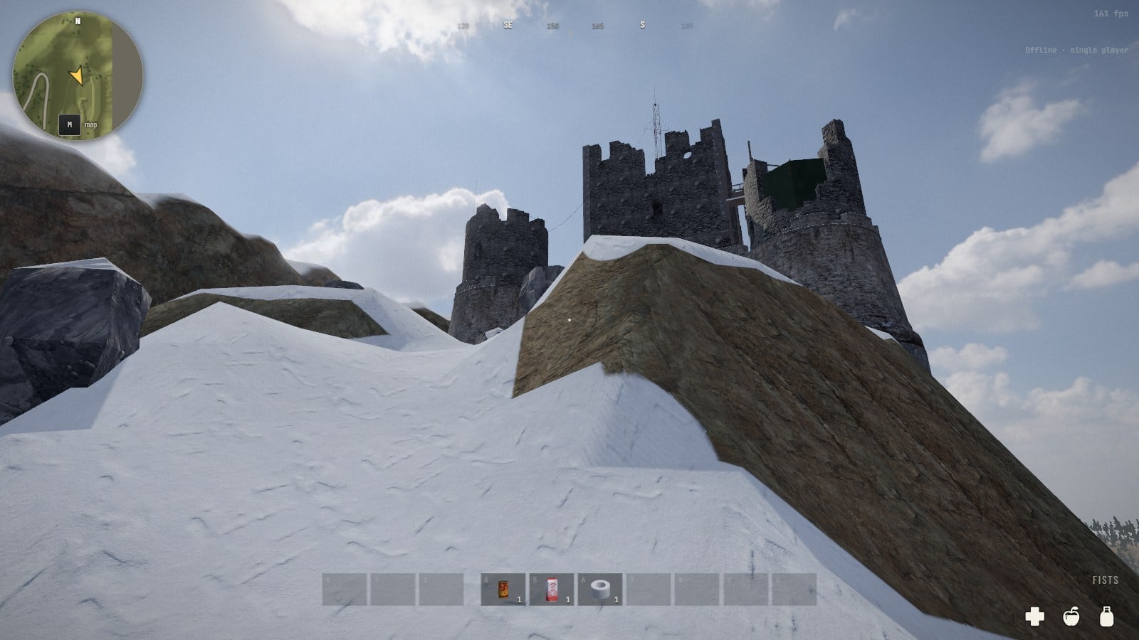 Looking up a slope of snow and a ramp of bare rock to the towers of the fort on the skyline, boulders on the left